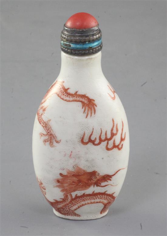 A Chinese iron red enamelled dragon snuff bottle, 19th century, height 7.6cm excl. coral and enamelled silver stopper